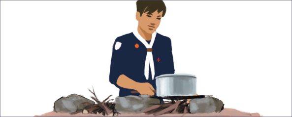 Scout qui cuisine sur une table à feu